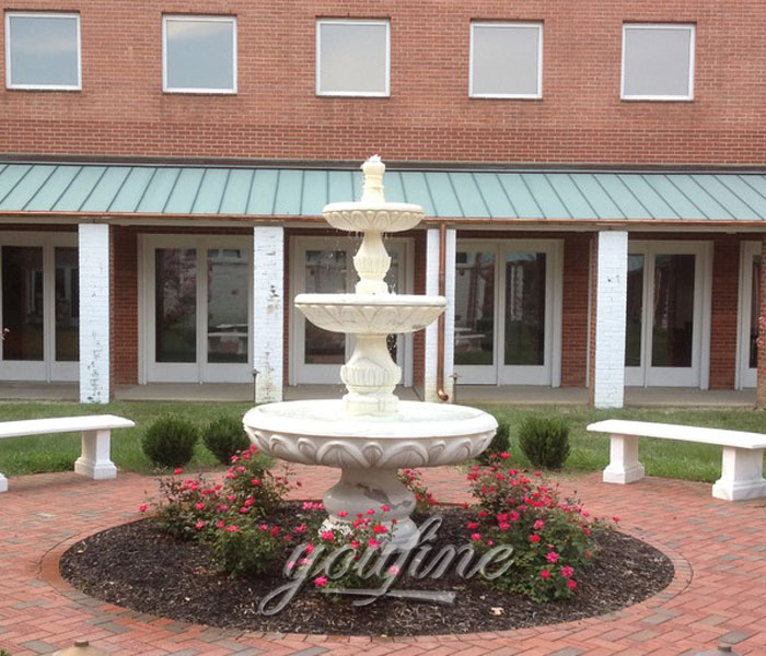 Tiered white marble water fountain in front of house